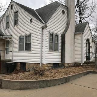 A white residential structure photographed at an angle with an entry door on each visible side.